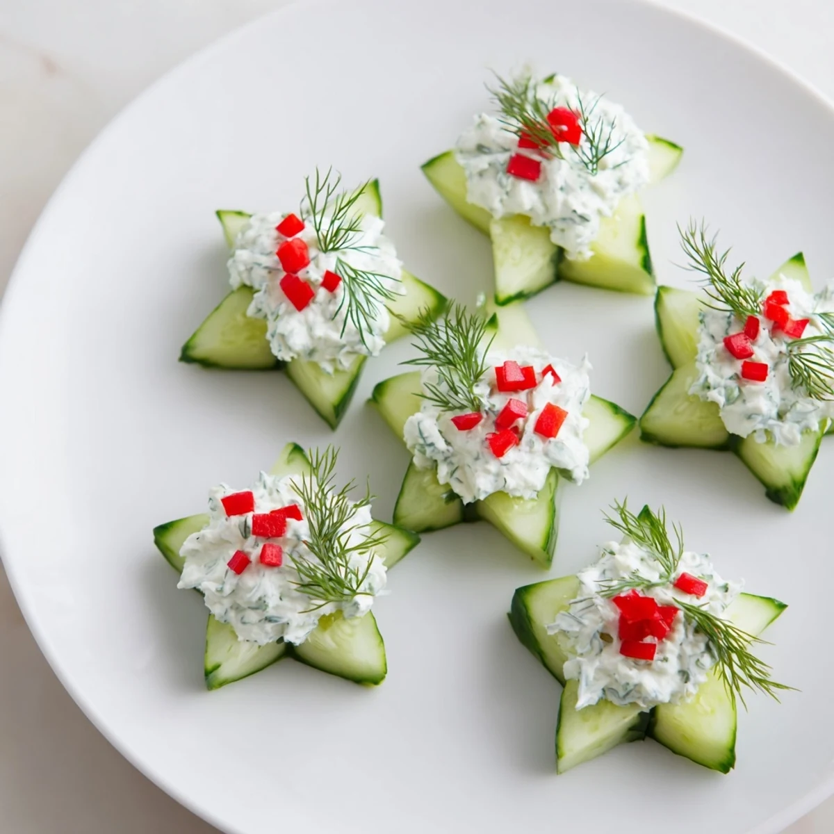 Bright red bell pepper garnishes the creamy dill topping of these cucumber and dill Christmas stars.