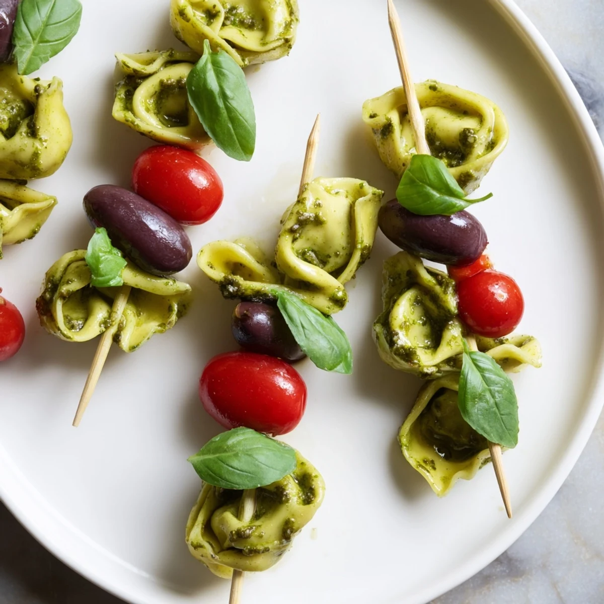 Tender appetizers: vibrant Appetizer Skewers showcasing pesto-coated tortellini, tomatoes, and olives ready to enjoy.