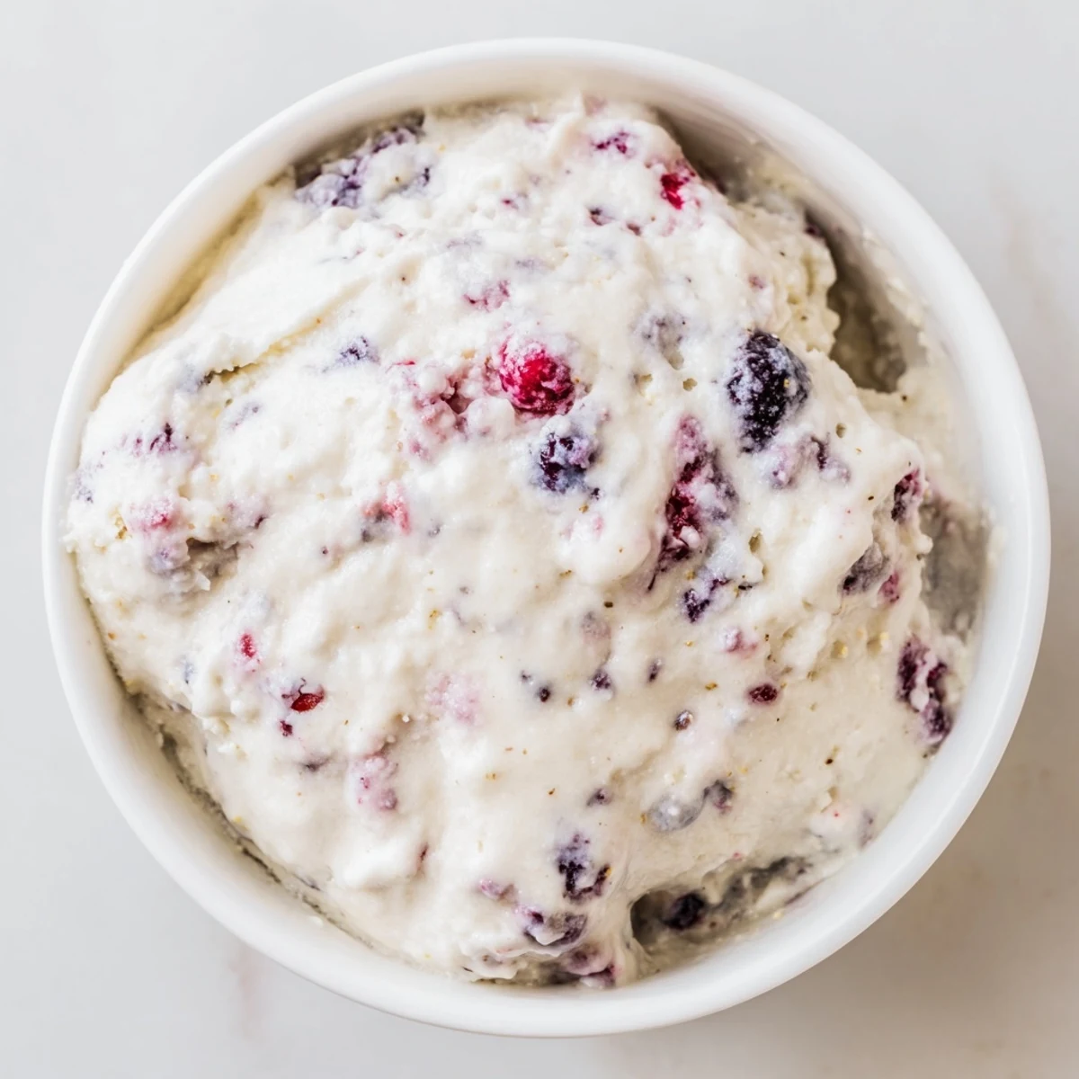 A refreshing bowl of cottage cheese ice cream, bursting with berry flavor, ideal for summer.