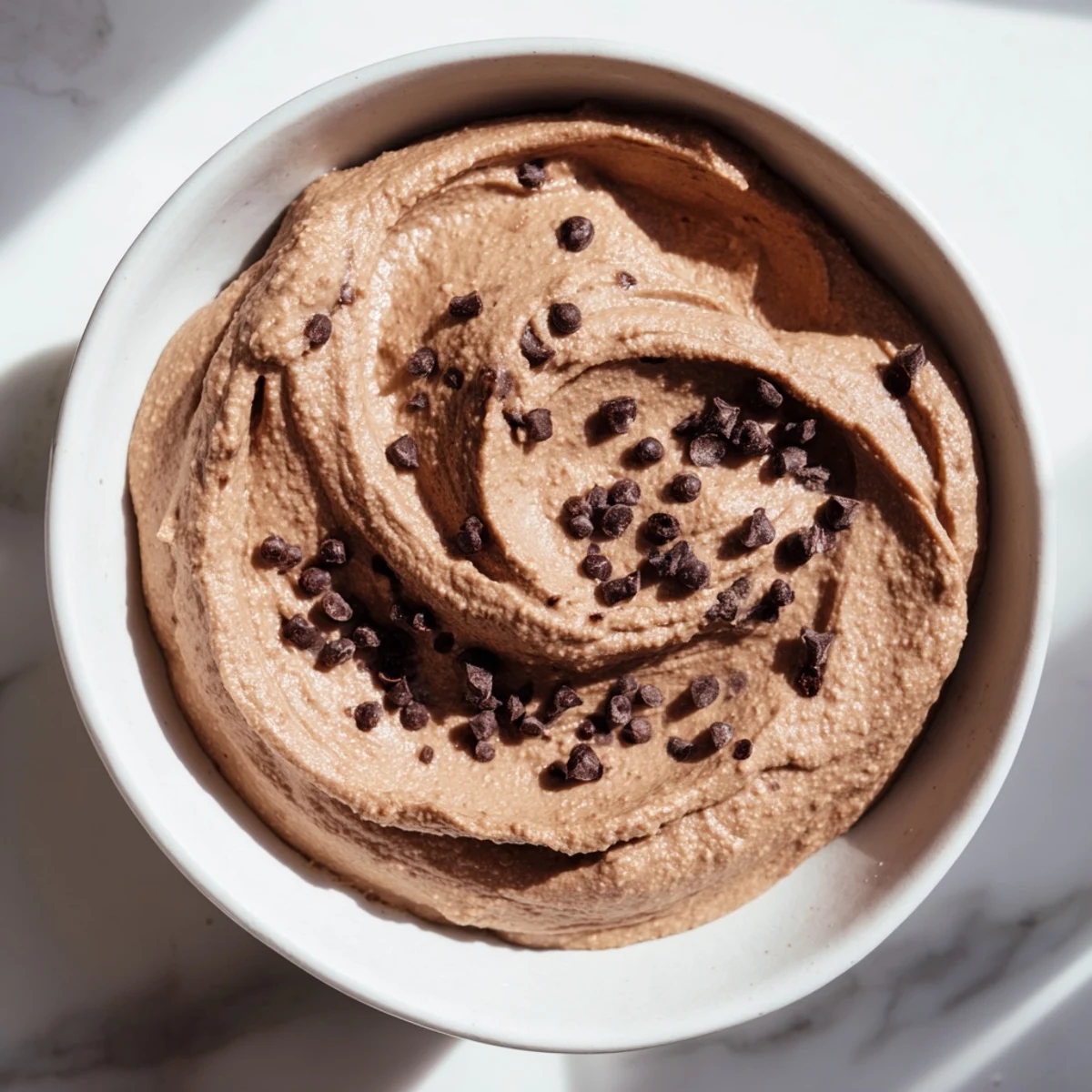 A bowl of rich, velvety Chocolate Hummus ready to be enjoyed with fresh fruit for dipping.