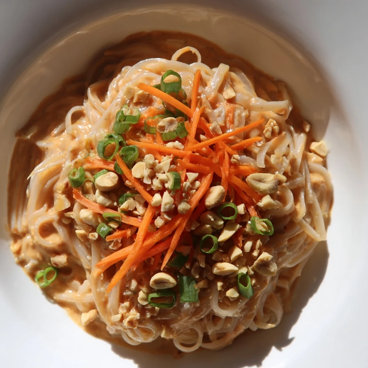 Steaming bowl of Spicy Peanut Noodles with vibrant veggies and peanuts, ready to enjoy.