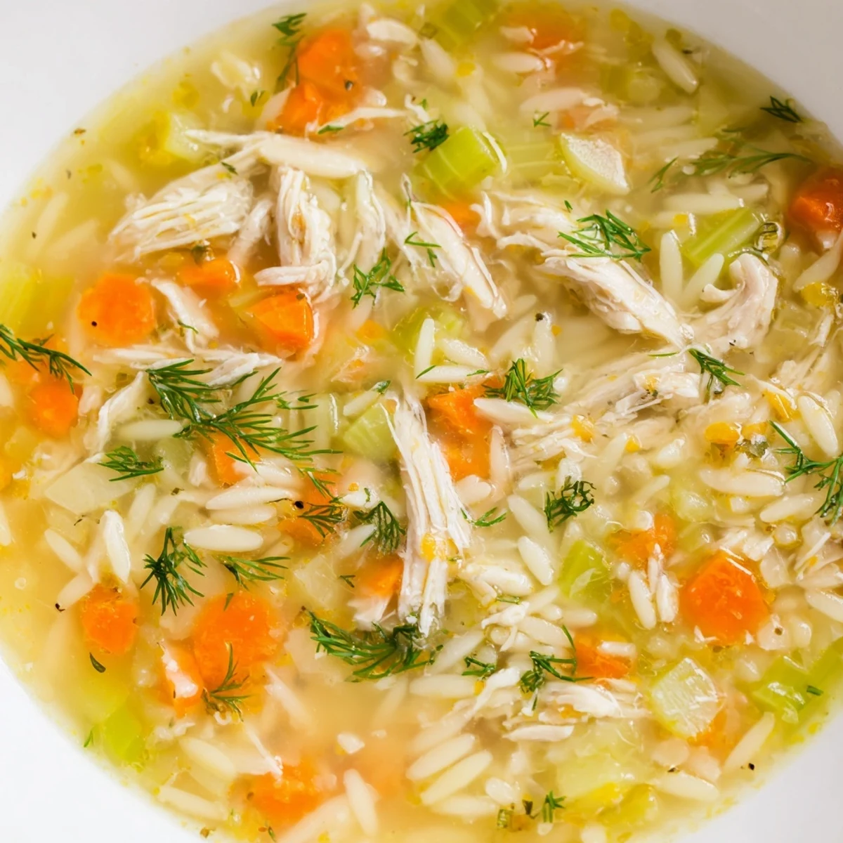 Vivid close-up of Chicken Lemon Orzo Soup featuring delicate orzo pasta and zesty lemon, ready to enjoy.