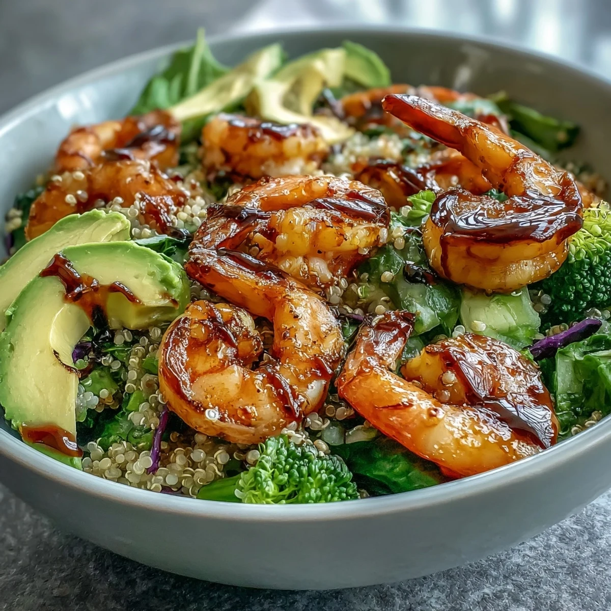Vibrant Rainbow Vegetable Detox Bowl topped with pink shrimp, creamy avocado slices, and fluffy quinoa, drizzled with tangy balsamic dressing for a healthy meal.