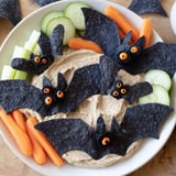 Festive Spooky Bat Bean Dip Platter on a platter with tortilla chips and fresh veggies.