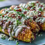 Microwave Elote-Style Corn with Cotija: golden cobs coated in creamy lime sauce, chili, and crumbly cheese, garnished with fresh cilantro.