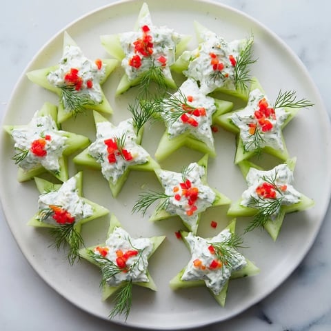 Cucumber and dill Christmas stars appetizer, featuring creamy cheese piped on festive cucumber shapes.