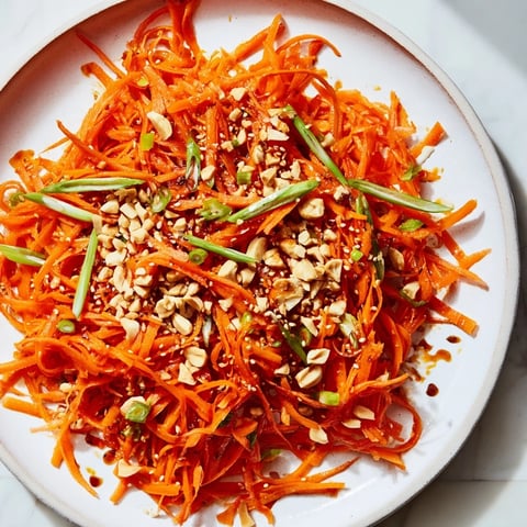 Vibrant Spicy Carrot Salad with shredded carrots, a fiery dressing, and a sprinkle of sesame seeds.
