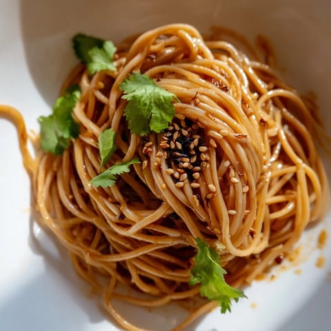 Chilled noodles tossed in a spicy sesame dressing with crisp cucumbers and fresh herbs for a refreshing salad.