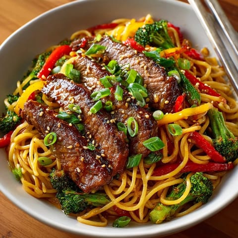 Sizzling stir-fry of Sticky Beef Noodles mixed with red peppers, broccoli, and green onions.