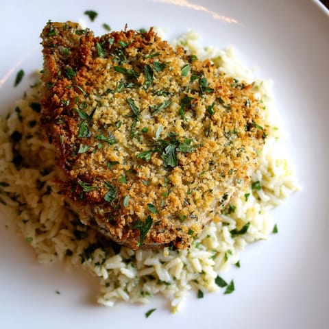 Crispy-crusted Parmesan Herb Pork Chops with steam rising, plated over seasoned rice for dinner.