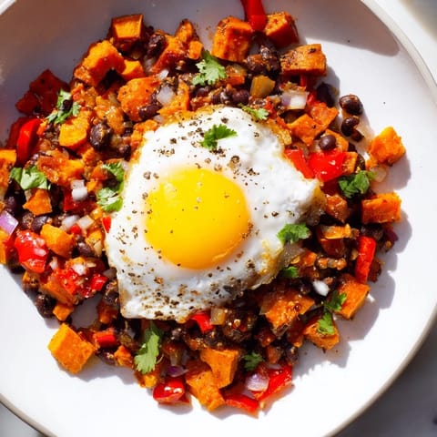 This delicious Sweet Potato & Black Bean Breakfast Hash showcases vibrant veggies with sunny-side-up eggs ready to serve.