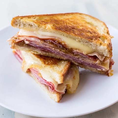 Delicious charcuterie grilled cheese, a gourmet sandwich showing layers of cheese and cured meats.