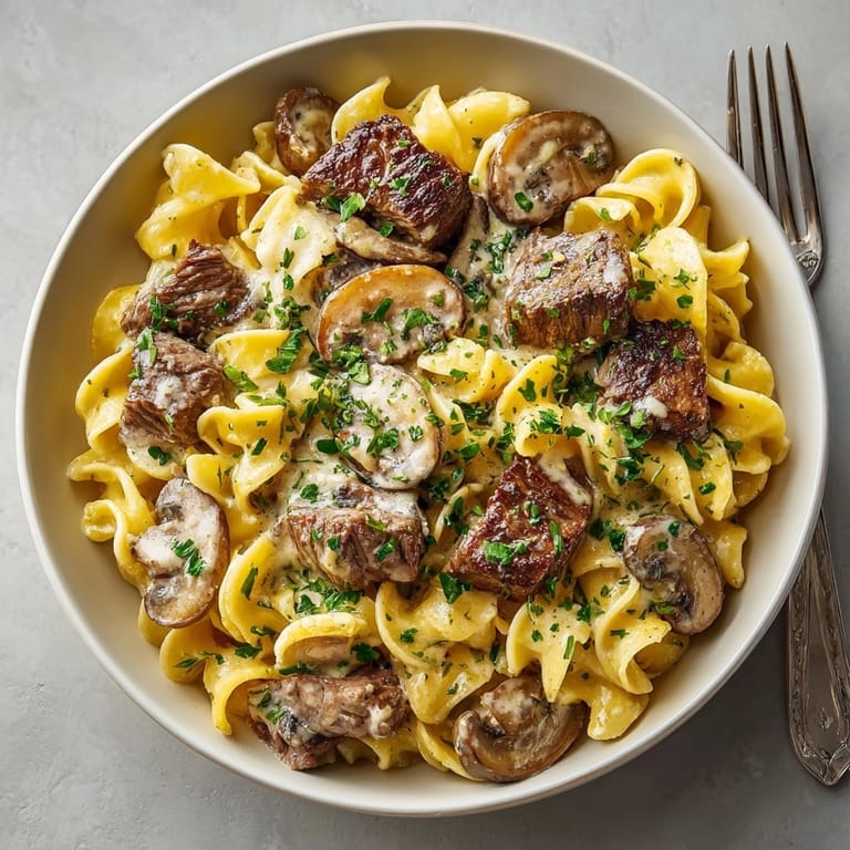 Steaming one-pot beef stroganoff with mushrooms and egg noodles, perfect for cozy autumn dinners.