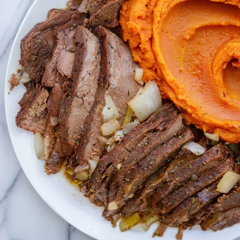 Fork-tender Classic Brisket, glistening with sauce, next to creamy, dreamy mashed sweet potatoes.