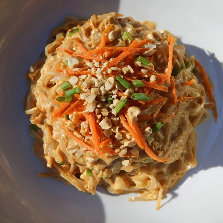 Delicious serving of Spicy Peanut Noodles topped with fresh herbs, offering a flavorful bite.