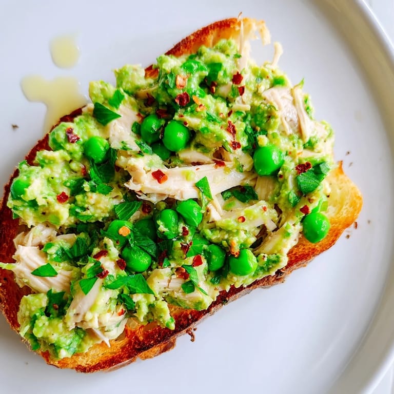 Savory open-faced chicken and pea toast served warm, featuring bright lemon and a hint of chili heat.