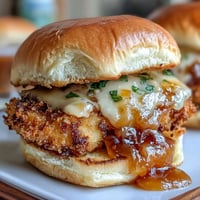 Crispy fried chicken sliders topped with tangy honey mustard sauce and melted cheddar cheese.